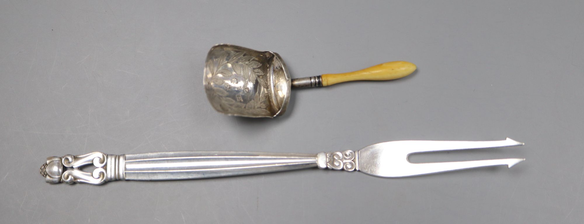 A 1950s Georg Jensen sterling pickle fork and a George III ivory handled silver caddy spoon.